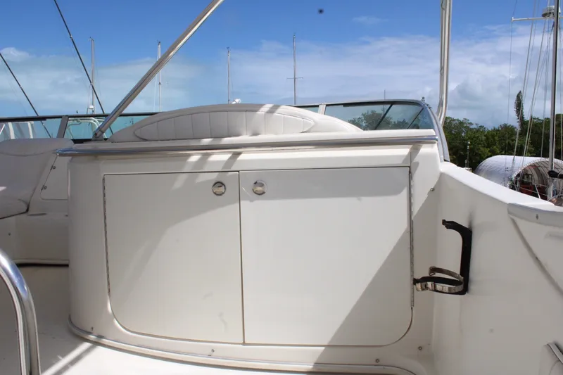 Slide: The Image of 1999 Maxum 4600 SCB yacht deck with white cabinetry and seating under blue sky. - 26