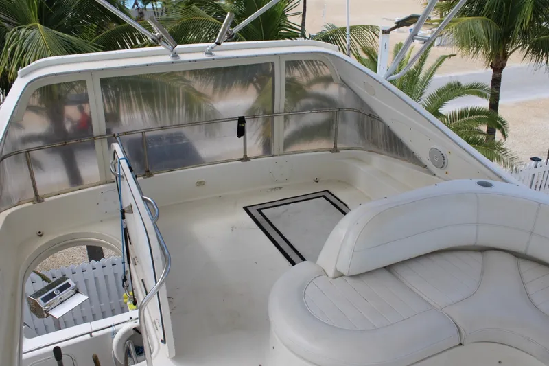 Slide: The Image of 1999 Maxum 4600 SCB yacht deck with white seating and palm trees in background. - 27