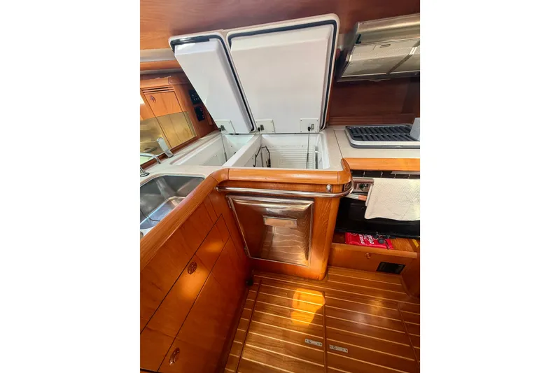 Slide: The Image of 2008 Jeanneau Sun Odyssey 49 DS yacht kitchen with open fridge and wooden cabinetry. - 62