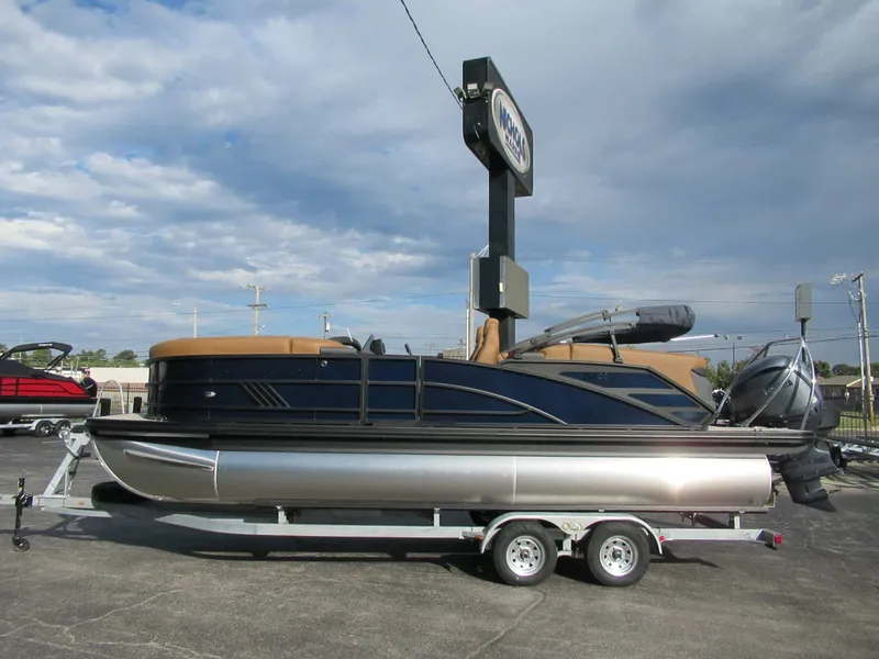 The Image of Bennington 22 MFB pontoon boat on a trailer, featuring blue and brown design, under cloudy sky. - 0
