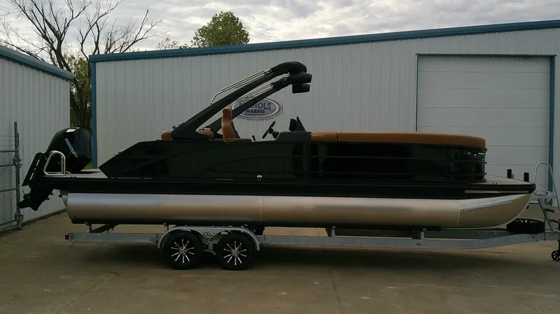 Slide: The Image of 2027 Bennington M 26 pontoon boat on a trailer, featuring a sleek black and brown design. - 1