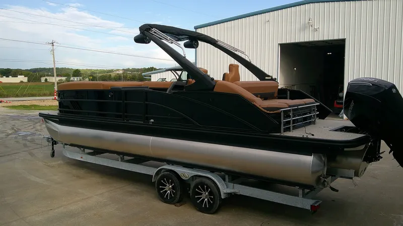 Slide: The Image of A sleek Bennington M 26 pontoon boat on a trailer outside a warehouse. - 6