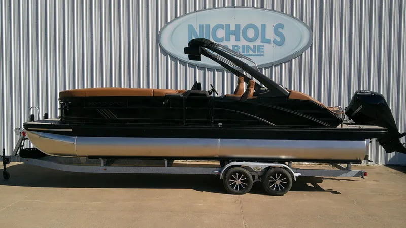 The Image of A 2027 Bennington M 26 pontoon boat on a trailer in front of a building. - 0