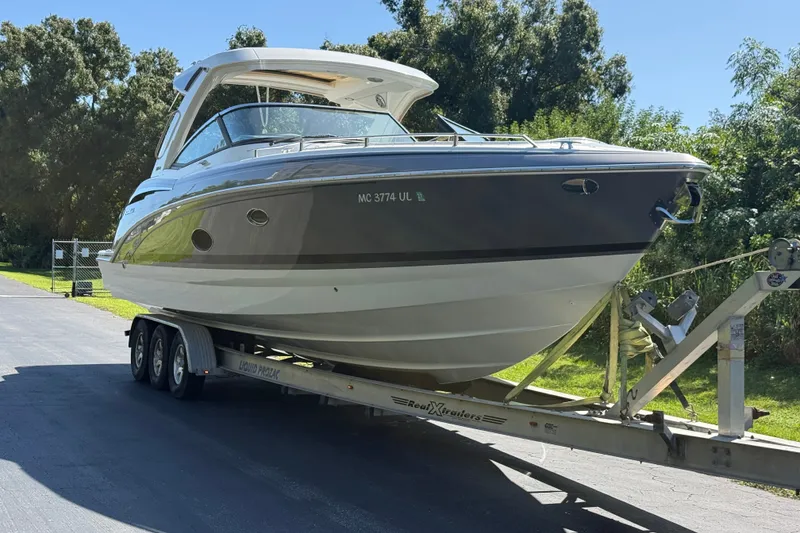 Slide: The Image of 2020 Formula 350 Crossover Bowrider on trailer, parked outdoors, surrounded by trees. - 4