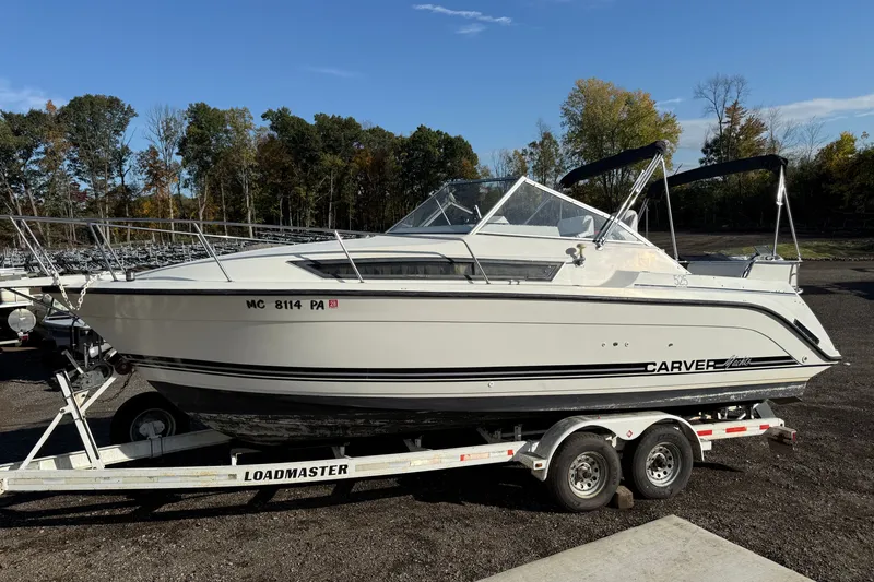 Slide: The Image of 1991 Carver 25 Montego boat on trailer, parked outdoors under clear sky. - 2