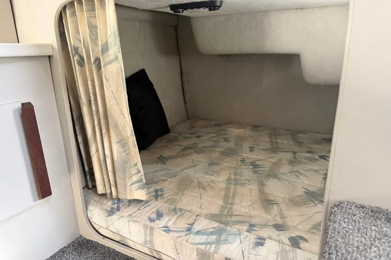 Slide: The Image of 1991 Carver 25 Montego cabin interior with patterned bedding and curtain. - 13