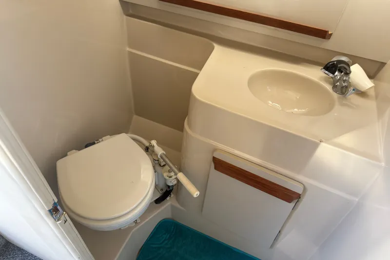 Slide: The Image of Compact bathroom in a 1991 Carver 25 Montego boat, featuring a toilet and sink. - 15