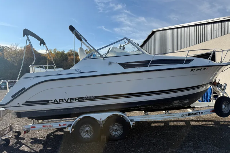 The Image of 1991 Carver 25 Montego boat on trailer, parked outdoors near a building. - 0
