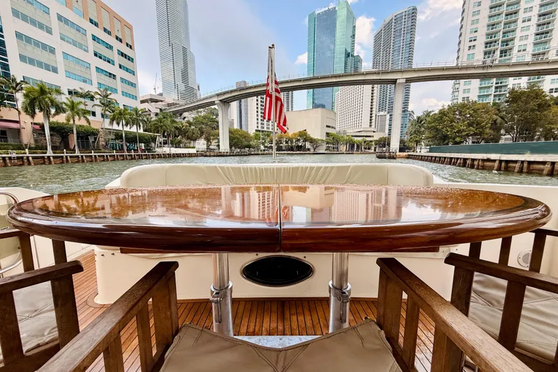 Slide: The Image of 2007 Azimut 68E yacht with polished wooden table, cityscape view, and American flag. - 64