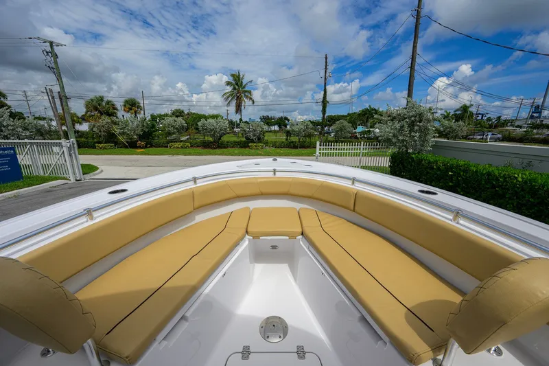 Slide: The Image of 2024 Sportsman Open 232 Center Console boat with tan seating, under a partly cloudy sky. - 21