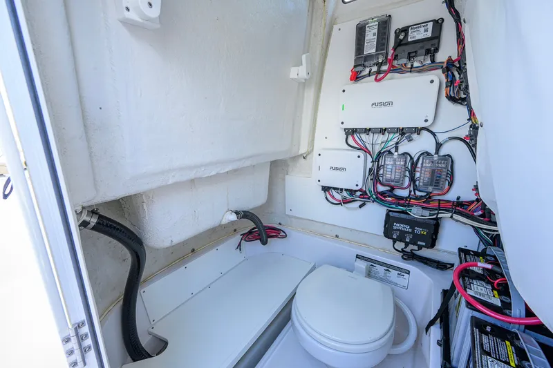 Slide: The Image of 2024 Sportsman Open 232 Center Console boat interior with wiring and marine toilet. - 52