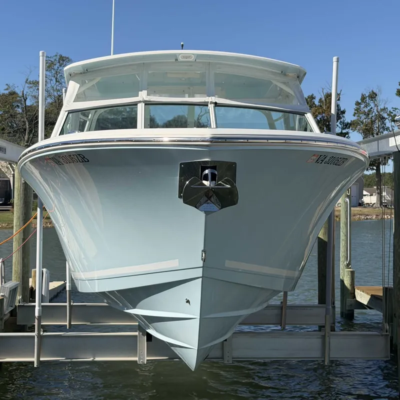 Slide: The Image of Cobia 330 Dual Console 2023 on a boat lift, surrounded by water and trees. - 2
