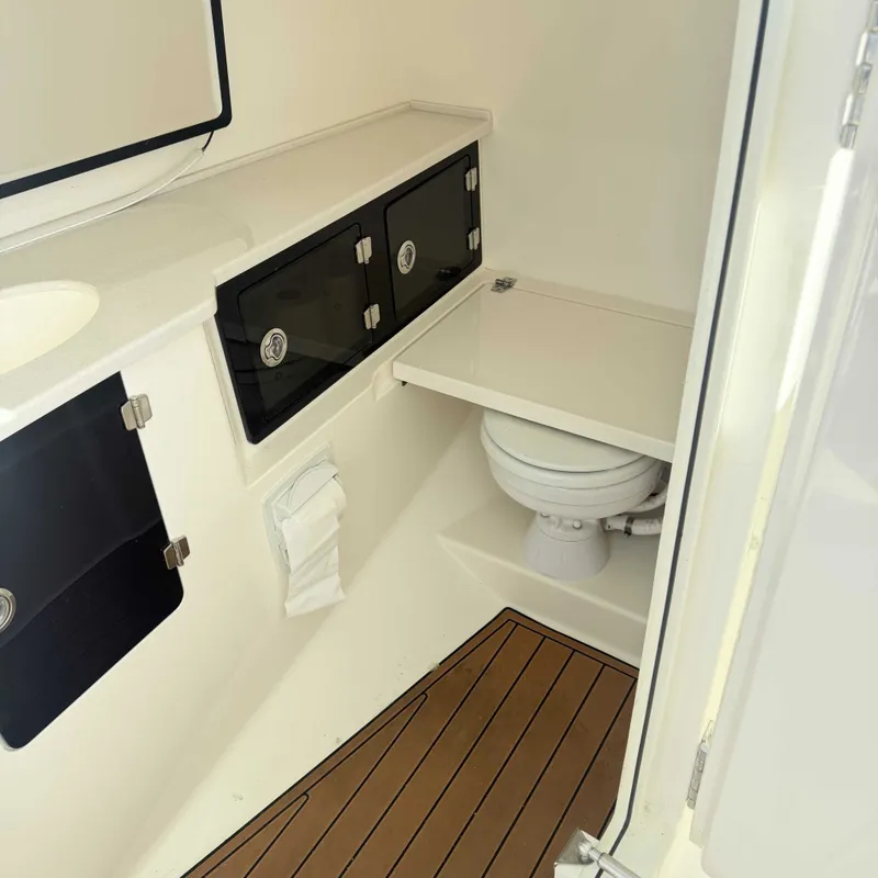 Slide: The Image of Interior of a 2023 Cobia 330 Dual Console with toilet and storage compartments. - 12