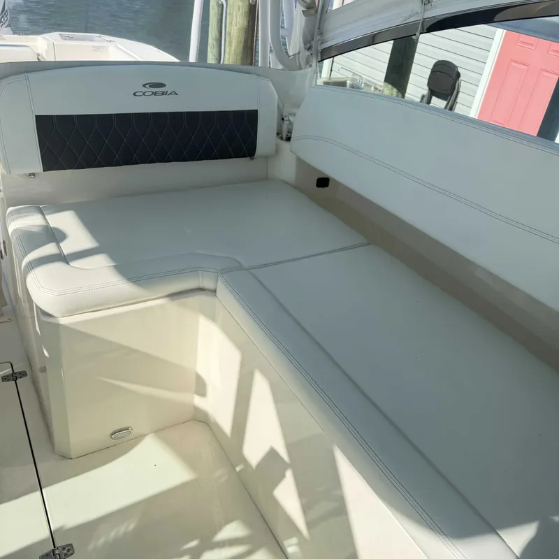 Slide: The Image of The 2023 Cobia 330 Dual Console features a spacious, cushioned seating area with a sleek, modern design. - 11
