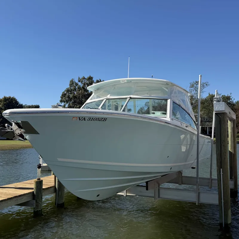 Slide: The Image of A 2023 Cobia 330 Dual Console boat on a lift at a dock. - 3