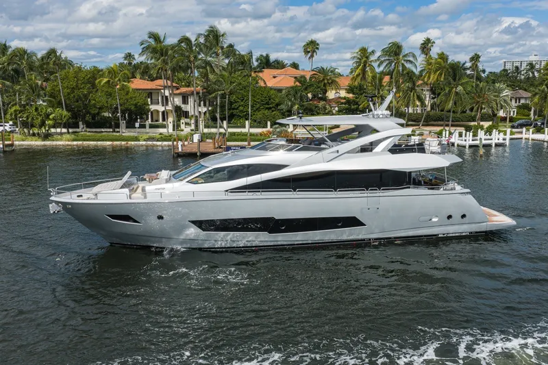 Slide: The Image of Luxurious 2018 Sunseeker 86 Yacht cruising near palm-lined waterfront homes. - 2
