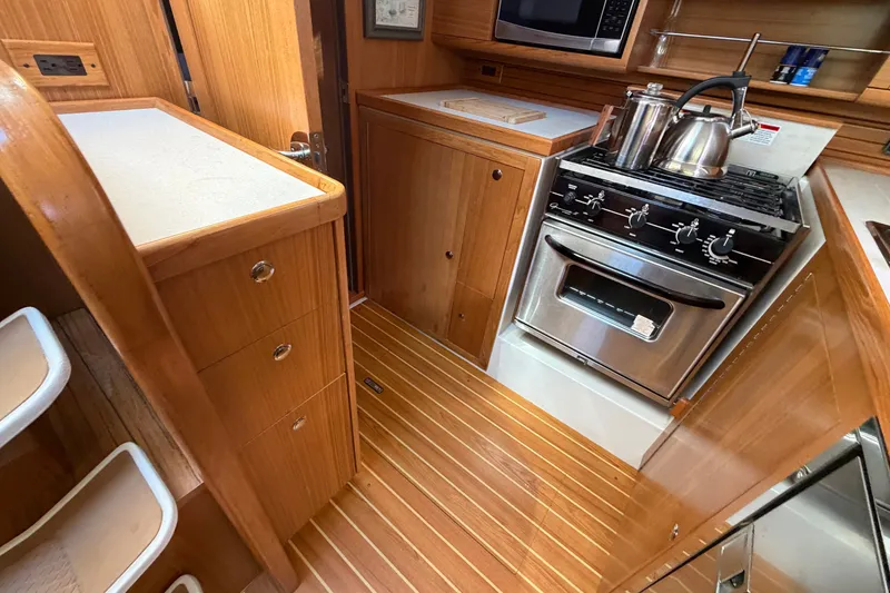 Slide: The Image of 2014 Catalina 445 yacht kitchen with wooden cabinetry, stove, and microwave. - 31
