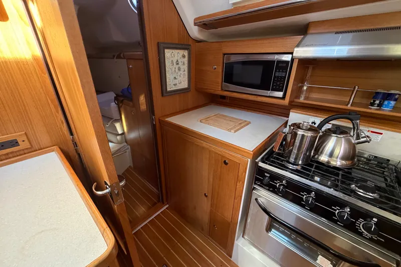 Slide: The Image of Cozy kitchen in 2014 Catalina 445 yacht with stove, microwave, and wooden cabinetry. - 32