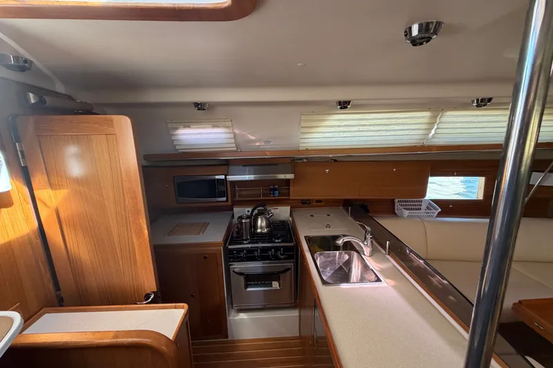 Slide: The Image of Interior of 2014 Catalina 445 sailboat kitchen with stove, sink, and wooden cabinetry. - 29