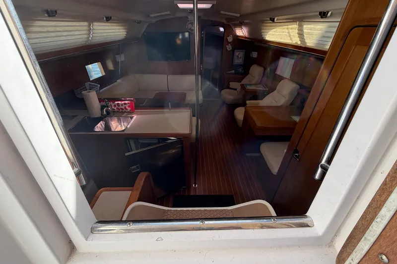 Slide: The Image of Interior view of a 2014 Catalina 445 yacht, featuring a cozy seating area and kitchenette. - 27