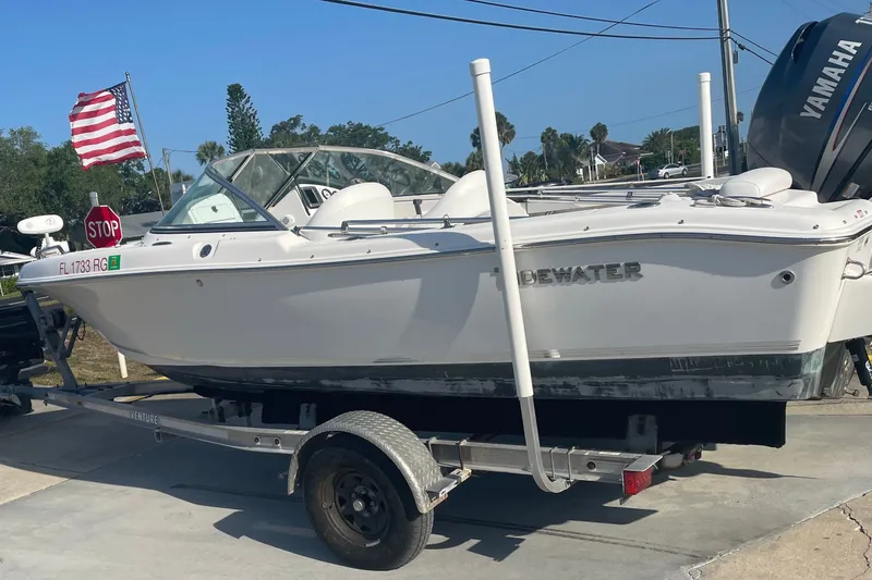 Slide: The Image of A white 2011 Tidewater 196 DC Explorer boat on a trailer with a US flag. - 1