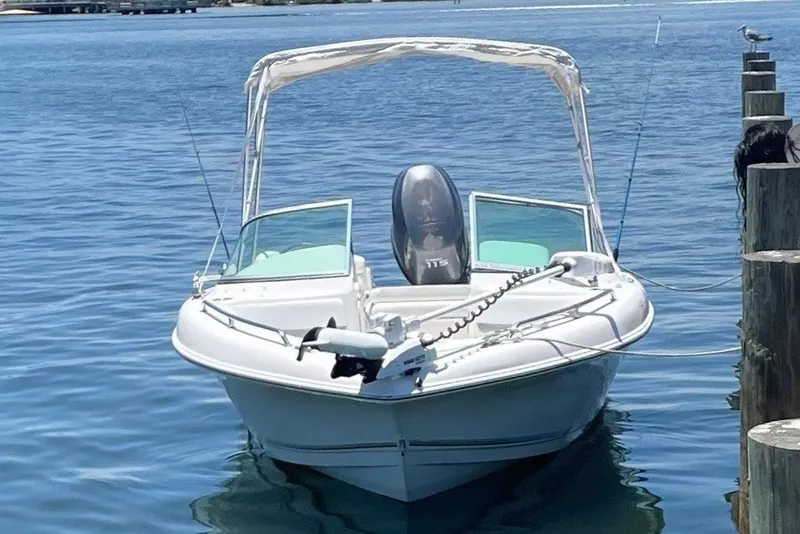 The Image of A white boat with an open canopy is docked in clear water. - 3