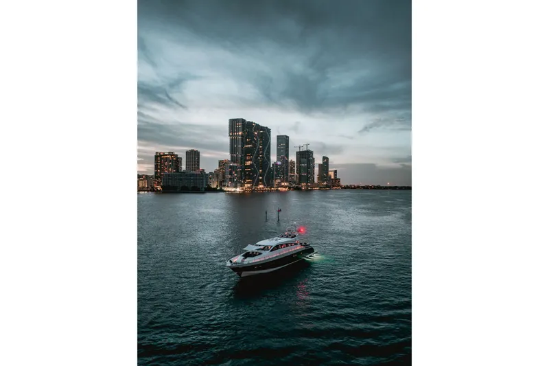 Slide: The Image of Luxury yacht Arno Leopard 31 (2006) cruising near illuminated city skyline at dusk. - 2