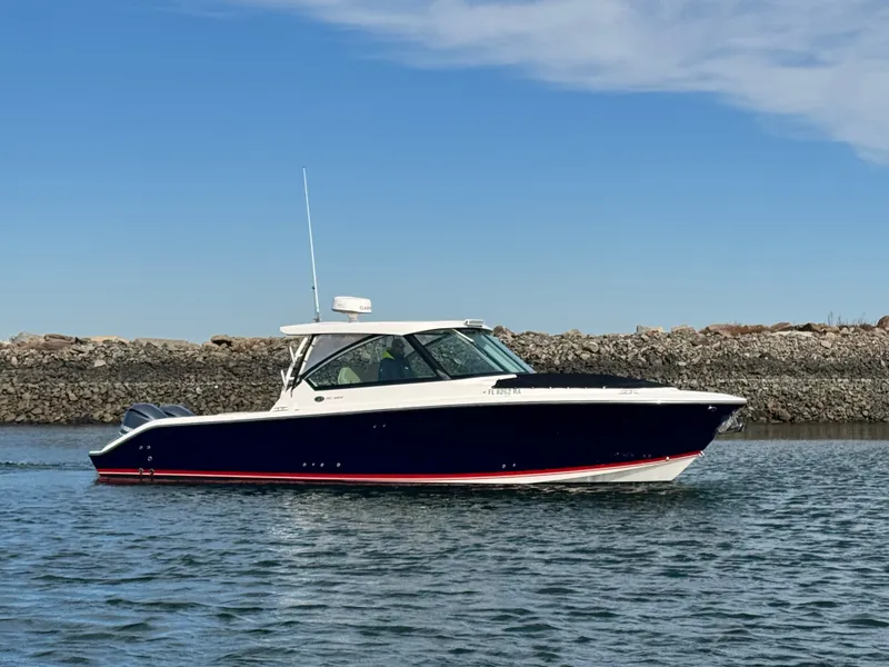 Slide: The Image of 2016 Pursuit DC 325 Dual Console on calm water near a stone wall. - 1