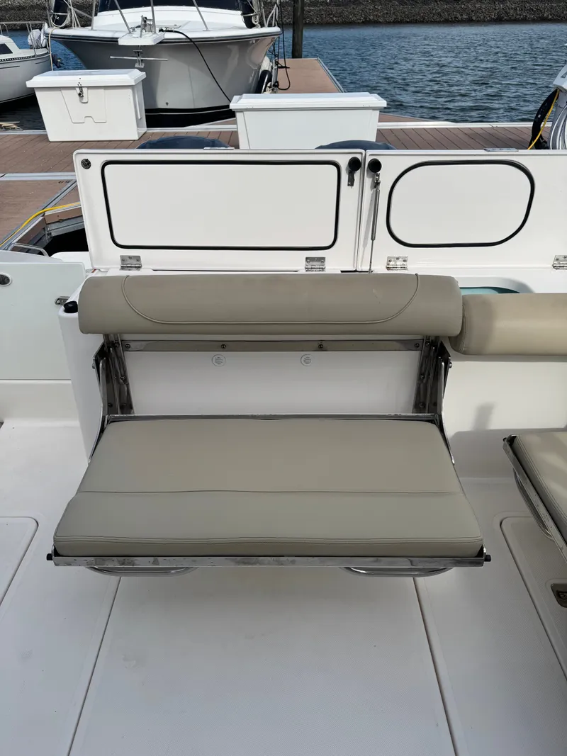 Slide: The Image of The 2016 Pursuit DC 325 Dual Console features a beige fold-down bench in the cockpit area. - 20