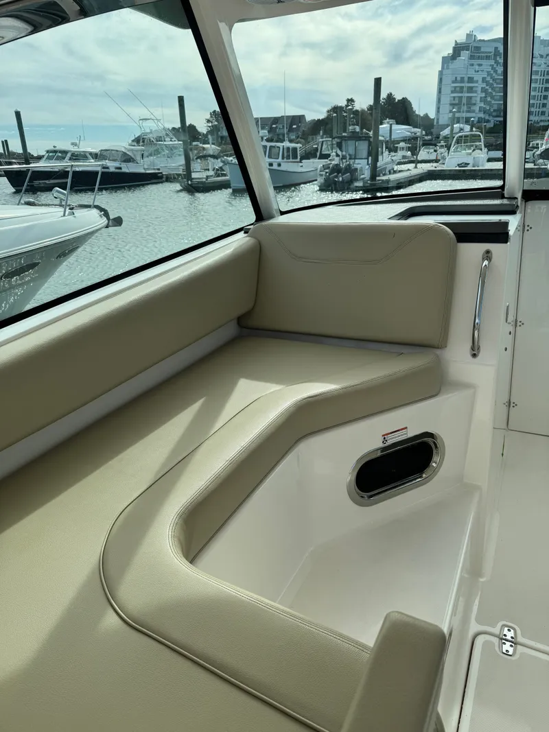 Slide: The Image of Interior view of a 2016 Pursuit DC 325 Dual Console with beige seating and a marina view. - 15