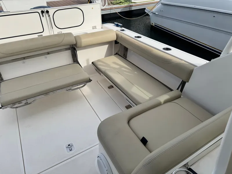 Slide: The Image of The image shows the seating area of a 2016 Pursuit DC 325 Dual Console boat with beige upholstery. - 17