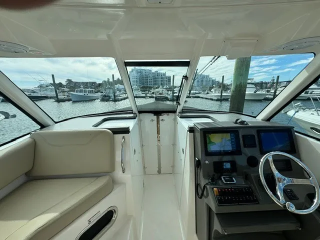 Slide: The Image of Interior view of a 2016 Pursuit DC 325 Dual Console boat with helm and beige seating area. - 12