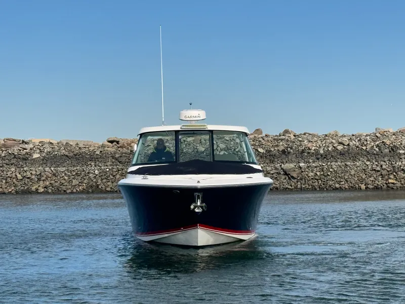 Slide: The Image of A 2016 Pursuit DC 325 Dual Console boat on the water near a rocky shoreline. - 4