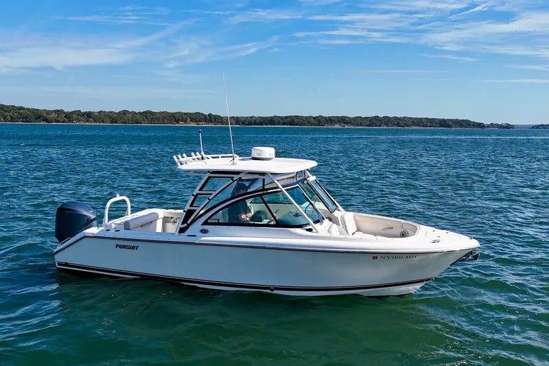 Slide: The Image of 2011 Pursuit DC 265 Dual Console boat on calm blue water under clear sky. - 2