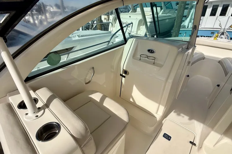 Slide: The Image of 2011 Pursuit DC 265 Dual Console boat interior with seating and cup holders. - 7