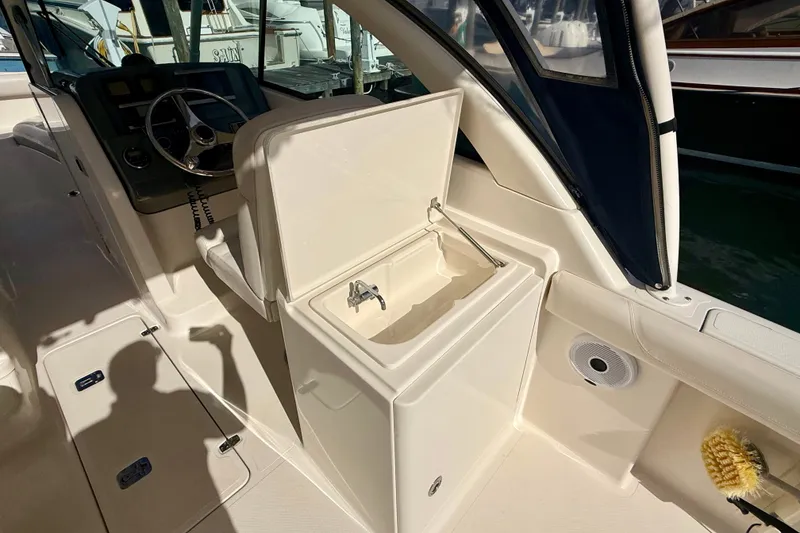 Slide: The Image of 2011 Pursuit DC 265 Dual Console boat interior with open storage compartment and steering wheel. - 28