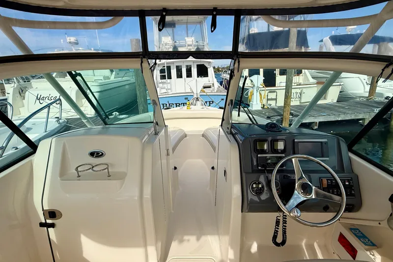 Slide: The Image of 2011 Pursuit DC 265 Dual Console boat interior with steering wheel and dashboard at marina. - 8