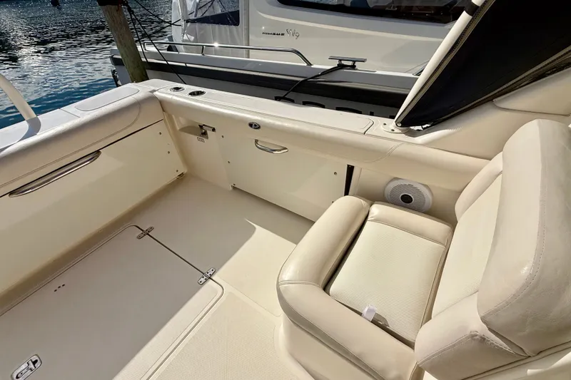 Slide: The Image of 2011 Pursuit DC 265 Dual Console boat interior with beige seating and storage compartments. - 19
