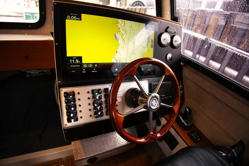 Slide: The Image of The cockpit of a KingFisher 3425 GFX Offshore with a large navigation screen and wooden steering wheel. - 15