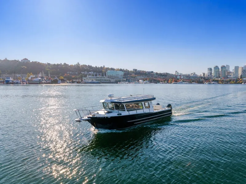The Image of KingFisher 3425 GFX Offshore 2022 on calm water with a cityscape in the background. - 3
