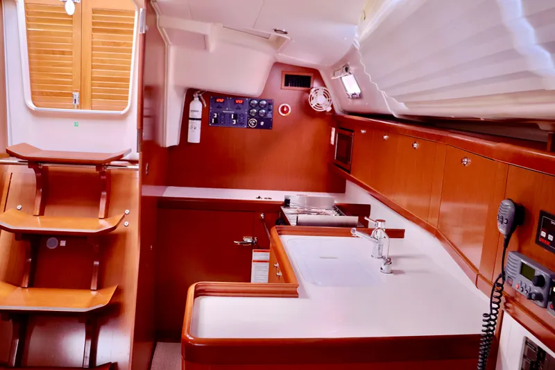Slide: The Image of Interior of a 2011 Beneteau 40 featuring wooden cabinetry and a compact kitchen area. - 7