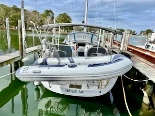 Slide: The Image of A 2011 Beneteau 40 docked in a calm marina, with a dinghy attached at the stern. - 1