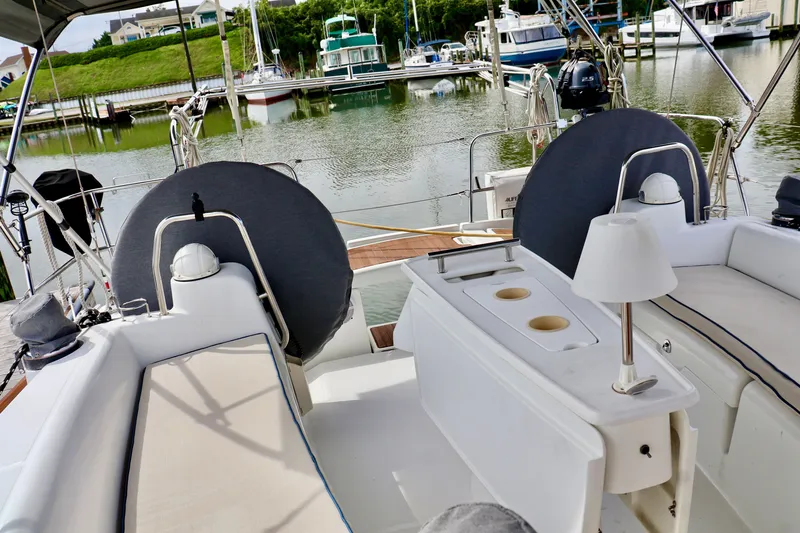 Slide: The Image of The cockpit of a 2011 Beneteau 40 with comfortable seating and a table, surrounded by a calm marina. - 24