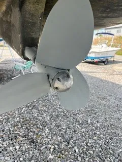 Slide: The Image of Close-up of a gray propeller on a boat, situated on a gravel lot. - 32