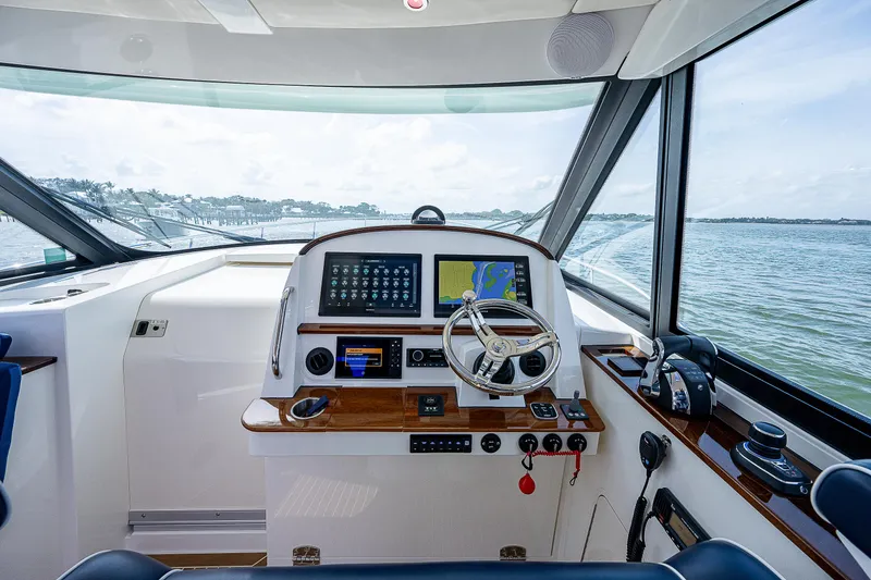 Slide: The Image of Das Cockpit einer modernen Yacht mit Steuer, Bildschirmen und Blick auf das Wasser. - 18