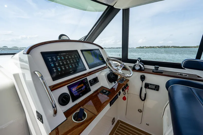 Slide: The Image of Steuerstand eines modernen Bootes mit Touchscreen-Displays und Ledersitzen, umgeben von Wasser. - 17