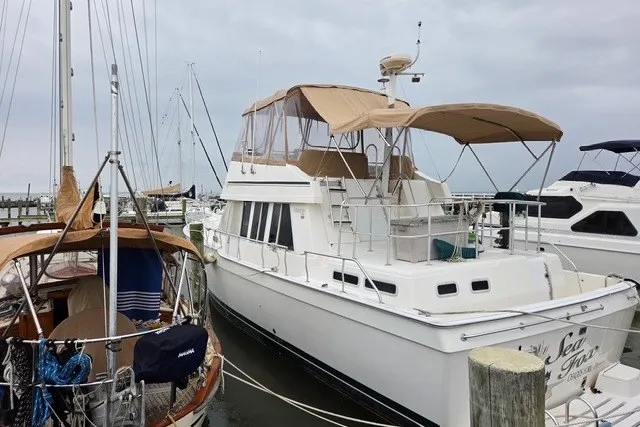 Slide: The Image of 2002 Mainship 430 Trawler docked at marina, featuring beige canopy and white hull. - 1