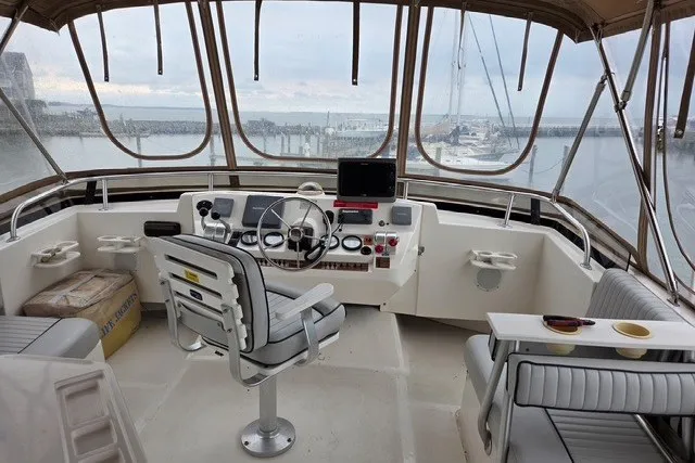Slide: The Image of 2002 Mainship 430 Trawler helm with marina view, featuring navigation equipment and seating. - 3
