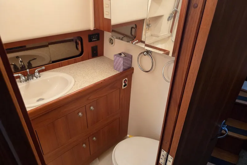 Slide: The Image of Bathroom interior of 2002 Mainship 430 Trawler with sink, mirror, and wooden cabinetry. - 18