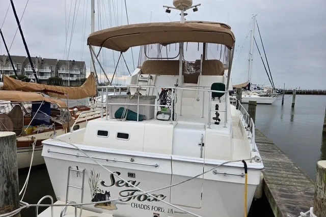 Slide: The Image of 2002 Mainship 430 Trawler docked at marina, featuring covered upper deck and sleek design. - 2
